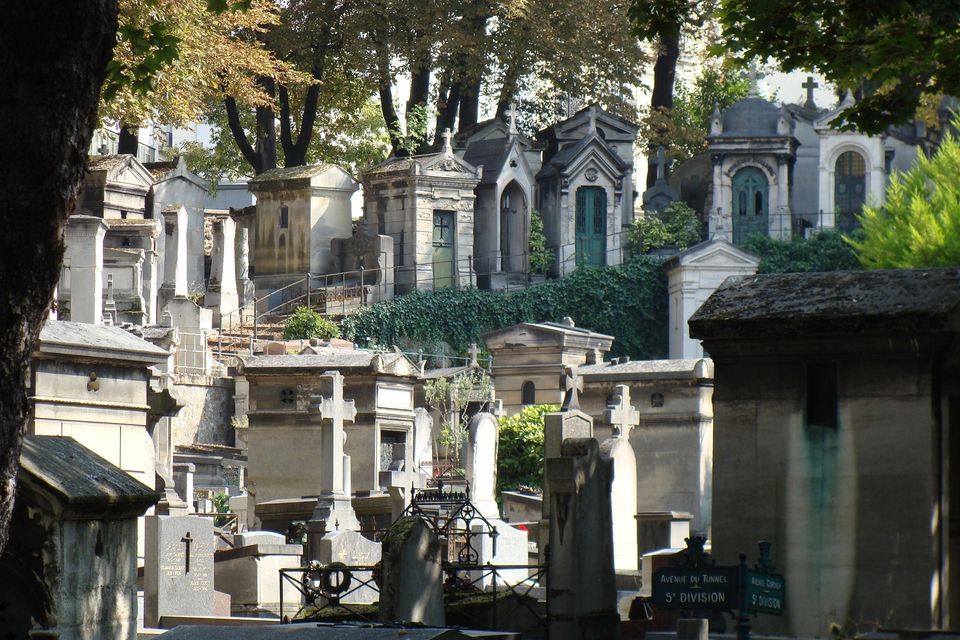 Stone tombs and mausoleums among trees in Montmartre Cemetery.