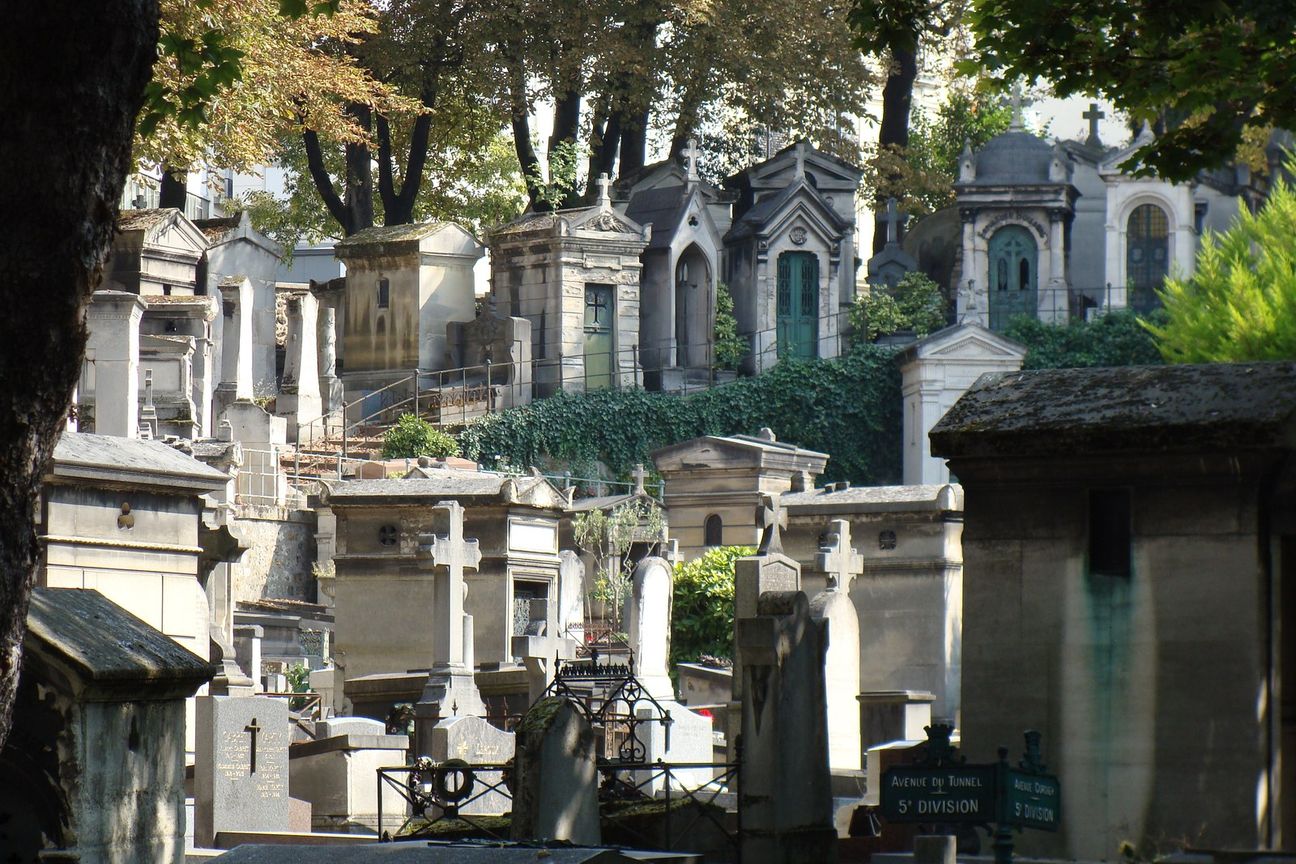 Stone tombs and mausoleums among trees in Montmartre Cemetery.