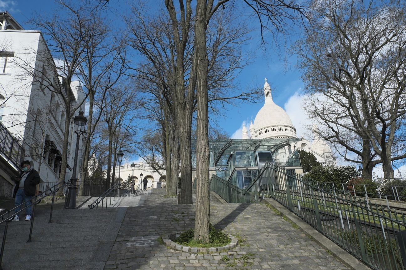Steps on Rue Foyatier beside the funicular, with trees and the Sacré-Cœur dome above.