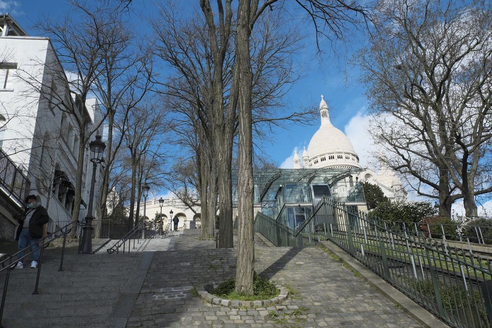 Steps on Rue Foyatier beside the funicular, with trees and the Sacré-Cœur dome above.