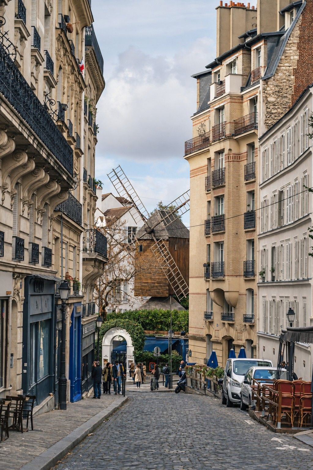 The Moulin de la Galette framed by Parisian facades at the end of a cobbled street.